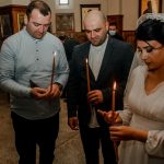 Bride and guests holding candles during an Orthodox wedding ceremony in a church setting.
